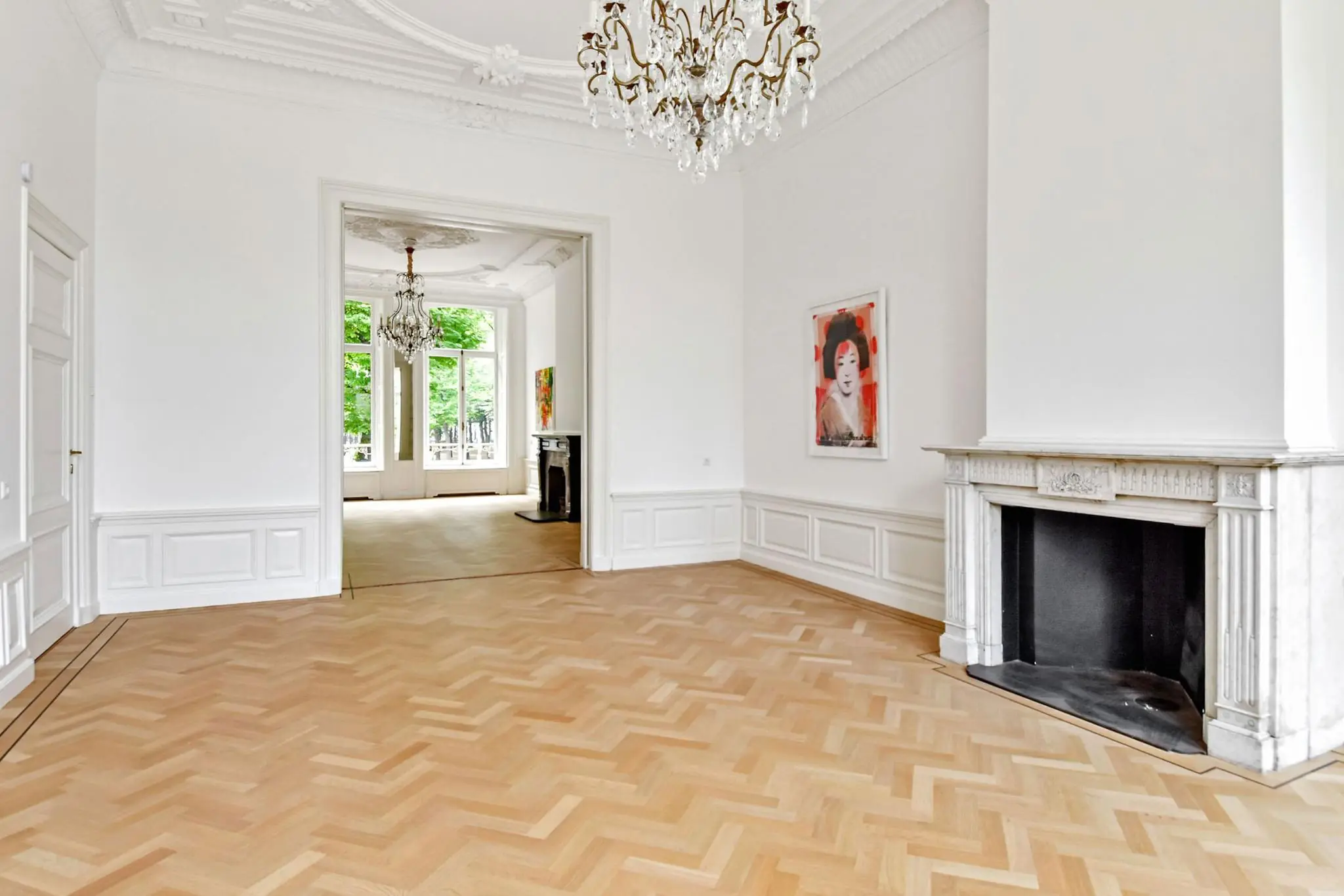 Luxe klassieke woonkamer aan het Lange Voorhout met visgraatvloer, marmeren schouw en kroonluchters.